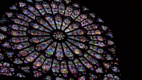 A-round-stained-glass-window-in-a-darkened-cathedral