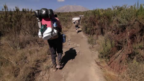 Headed-down-trail-behind-porters-Kilimanjaro-in-the-background