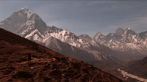 Trekker-headed-down-trail-peaks-in-background