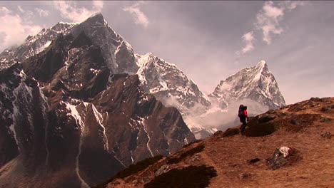 Trekker-climbing-steep-hill-with-large-peak-in-back