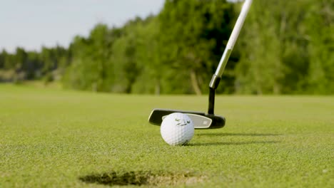 Slow-motion-close-up-of-a-putter-striking-a-golf-ball-and-sinking-a-short-putt