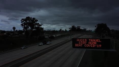 Aerial-sign-along-a-darkened-freeway-tells-people-to-avoid-travel-during-the-Covid19-coronavirus-epidemic-outbreak