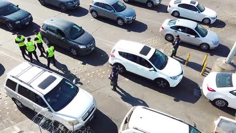 Agentes-De-La-Patrulla-Fronteriza-Esperan-Inspeccionar-Una-Línea-De-Autos-En-El-Cruce-Fronterizo-De-San-Ysidro,-Tijuana,-México