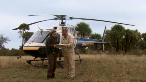 Ein-Polizeibeamter-Des-Wildlife-Refuge-Spricht-Mit-Einem-Hubschrauberpiloten-Und-Beobachtet,-Wie-Sein-Flugzeug-Abhebt