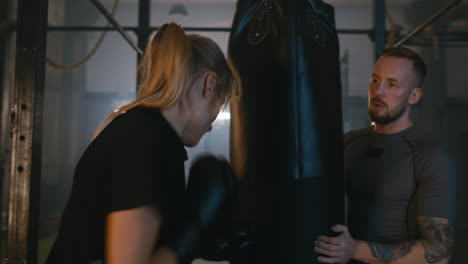 Mujer-y-entrenador-con-saco-de-boxeo