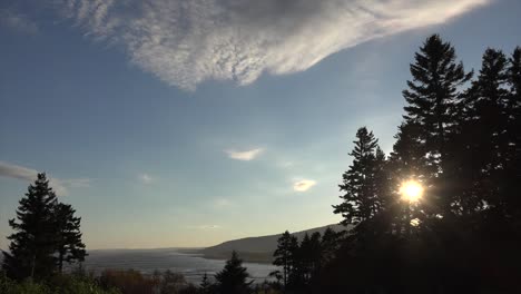 Canada-New-Brunswick-Sun-Through-Trees-On-Coast-With-Cloud