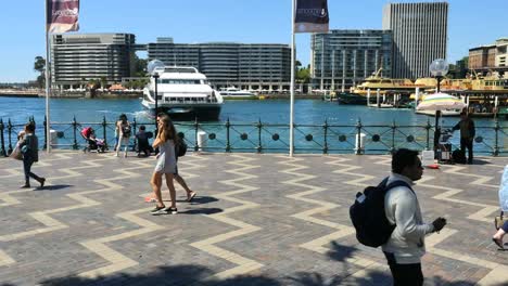 Australia-Sydney-People-Walking-By-Water-As-A-White-Boat-Turns-Around