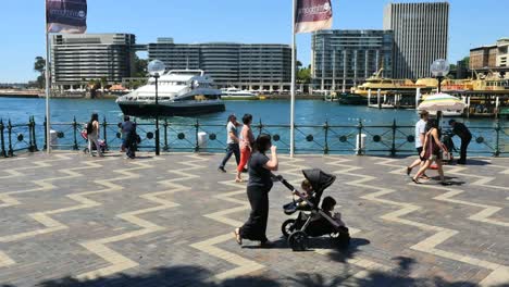 Australia-Sydney-Personas-Caminando-Por-El-Agua,-Incluida-La-Mujer-Con-Cochecito-De-Bebé