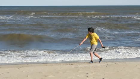 Virginia-Boy-Con-Un-Palo-Corre-A-Lo-Largo-De-La-Línea-De-Surf