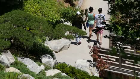 Gente-De-California-Caminando-Sobre-Un-Puente-Y-A-Través-De-Un-Jardín