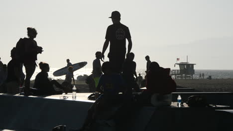 Los-Angeles-Venice-Beach-Junge-Skateboarder-Hinterleuchtet-Mit-Surfern-Darüber-Hinaus