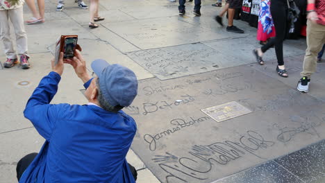 Los-Ángeles,-Un-Turista-Toma-Una-Foto-Con-Nombres-En-Concreto-En-El-Paseo-De-La-Fama-De-Hollywood