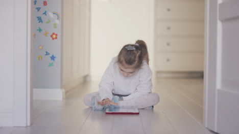 Girl-playing-tablet-on-floor-at-home