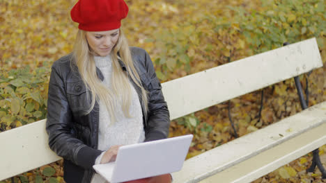 Pretty-woman-using-laptop-in-autumn-park