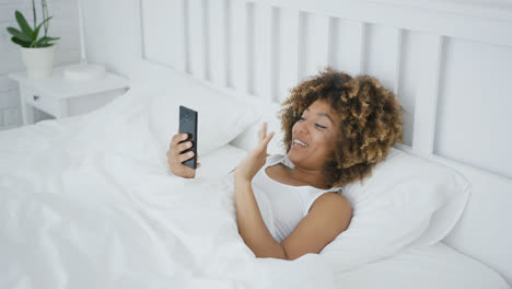 Smiling-woman-in-bed-talking-online