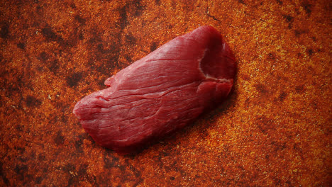 Piece-of-raw-fresh-beef-steak-placed-on-rusty-background
