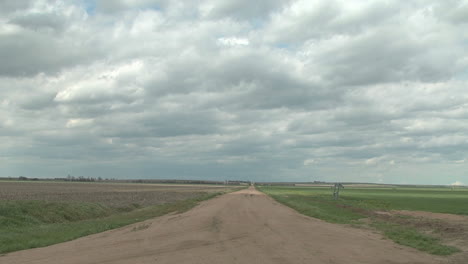 A-lonely-dirt-road-leads-across-the-Great-Plains-under-a-cloudy-sky