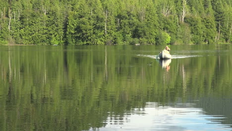 Canada-British-Columbia-Echo-Lake-canoe-approaches-on-calm-water