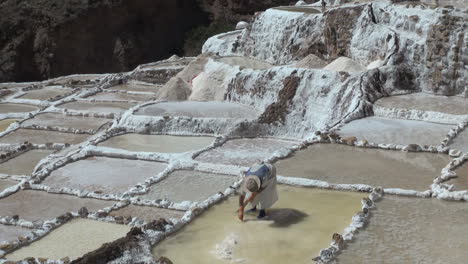 A-woman-works-to-pile-up-salt-in-a-salt-pan-in-the-Andes