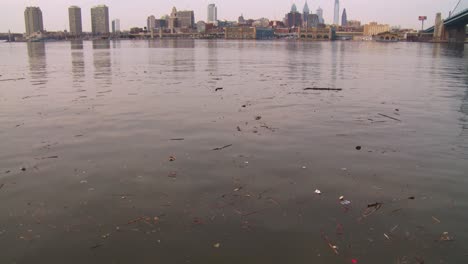 Tilt-up-to-ugly-brown-pollution-in-a-river-with-Philadelphia-Pennsylvania-background