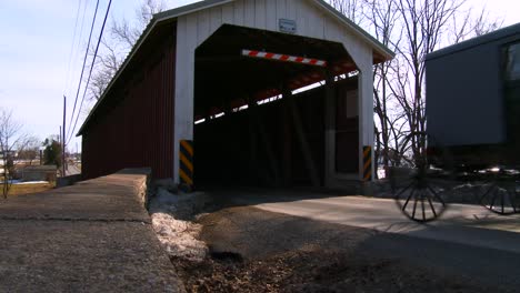 Ein-Amish-Pferdewagen-Fährt-Durch-Eine-überdachte-Brücke-Entlang-Einer-Straße-Im-Ländlichen-Pennsylvania-1