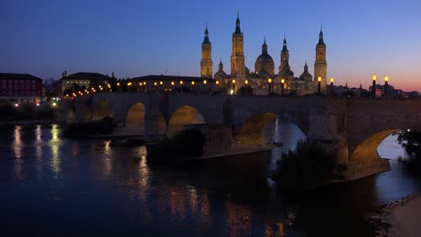 Un-Clásico-Y-Hermoso-Puente-De-Piedra-En-Zaragoza,-España-Al-Atardecer-Con-El-Fondo-De-La-Catedral-Católica