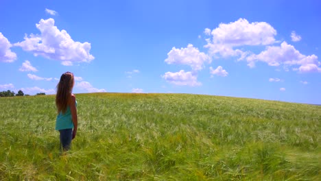 A-pretty-young-girl-stands-in-a-field-with-her-hair-blowing