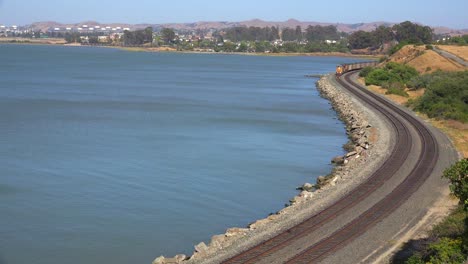 A-fast-moving-freight-train-passes-along-a-shoreline-in-the-Bay-Area-of-California
