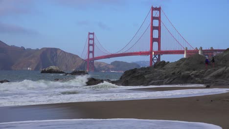 A-view-across-Baker-Beach-in-San-Francisco-to-the-Golden-Gate-Bridge-with-waves-crashing-on-shore