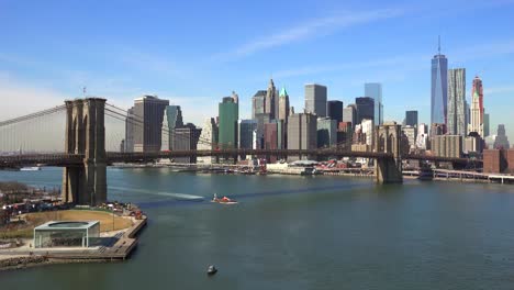 Bonito-Disparo-De-Establecimiento-Del-Distrito-Financiero-De-La-Ciudad-De-Nueva-York-Con-El-Puente-De-Brooklyn-En-Primer-Plano-Y-Los-Barcos-Que-Pasan-Por-Debajo