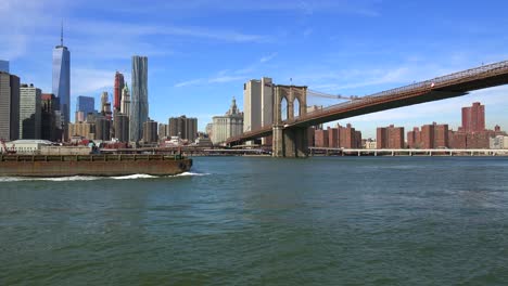 A-barge-and-tugboat-moves-up-New-York's-East-River-and-crosses-under-the-Brooklyn-Bridge