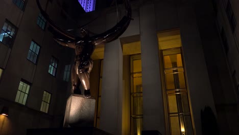 Tilt-Up-Shot-Para-Revelar-El-Rockefeller-Center-En-La-Ciudad-De-Nueva-York-Por-La-Noche-Con-La-Estatua-Del-Atlas-En-Primer-Plano