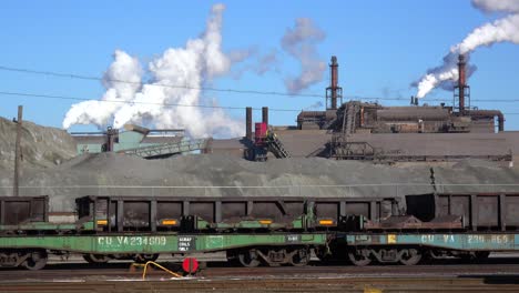 Global-warming-is-suggested-by-shots-of-a-steel-mill-belching-smoke-into-the-air-with-railcars-foreground