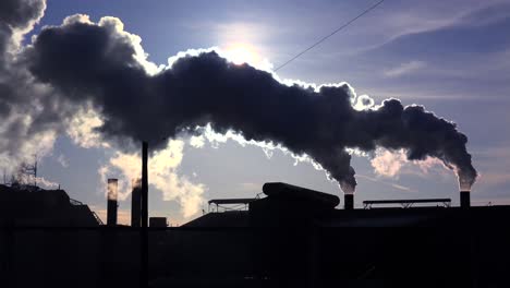 Global-warming-is-suggested-by-shots-of-a-steel-mill-belching-smoke-into-the-air-with-sun-background-4