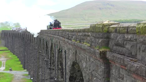 A-steam-train-passes-over-a-long-stone-viaduct-bridge-in-the-English-countryside