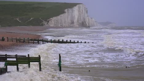 The-sea-breaks-along-wooden-jetties-along-the-shore-of-the-White-Cliffs-of-Dover-at-Beachy-Head-England