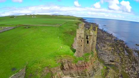 A-beautiful-vista-aérea-shot-over-an-abandoned-castle-along-the-North-Coast-of-Scotland