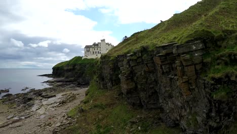 A-rising-aerial-shot-of-a-Scottish-castle-or-estate-along-a-cliff