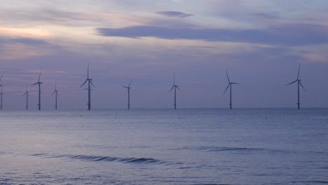 Ein-Windpark-Erzeugt-Bei-Sonnenuntergang-Strom-Entlang-Einer-Küste-1