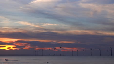 A-wind-farm-generates-electricity-along-a-coastline-at-sunset-5