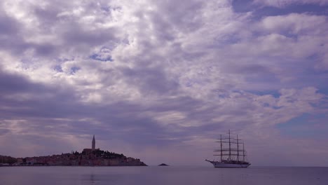 Beautiful-shot-of-the-town-of-Rovinj-in-Croatia-with-a-tall-masted-sailing-ship-in-distance