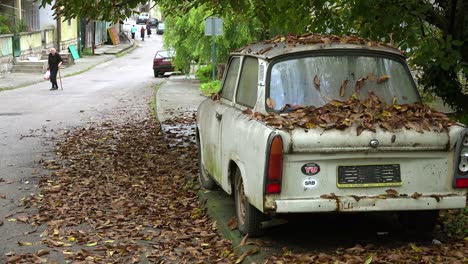 An-old-woman-walks-along-a-road-near-an-abandoned-car-in-a-rural-region-in-Russia