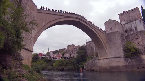Toma-De-Establecimiento-Del-Famoso-Puente-Stari-Most-En-Mostar,-Bosnia-Y-Herzegovina-Con-Un-Hombre-Saltando