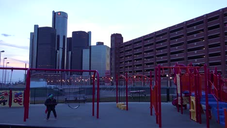 The-GM-tower-at-dusk-along-the-Detroit-Río-in-Detroit-Michigan-with-niños-playing-foreground