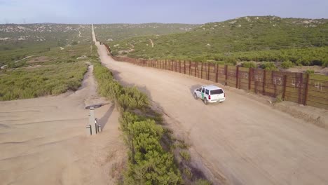 Vista-Aérea-over-a-border-patrol-vehicle-standing-guard-near-the-border-wall-at-the-US-Mexico-border-1