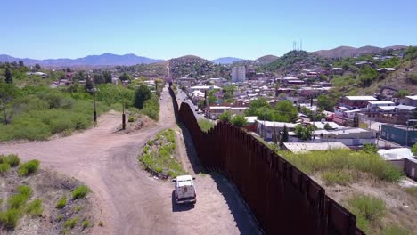 Aerial-over-a-border-patrol-vehicle-standing-guard-near-the-border-wall-at-the-US-Mexico-border-at-Tecate