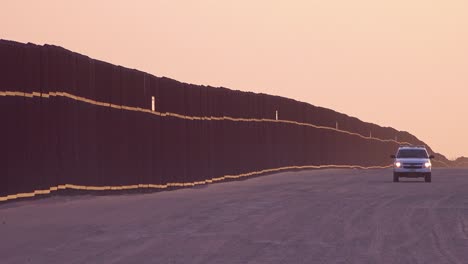 Border-patrol-vehicle-watches-near-the-border-wall-at-the-US-Mexico-border-at-Imperial-sand-dunes-California