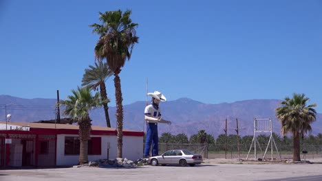 Eine-Große-Cowboy-Statue-Steht-Vor-Einer-Wüstenbar-Oder-Einem-Saloon-1