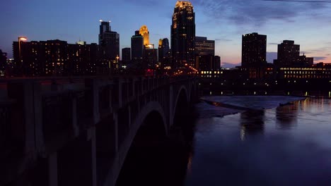 Eine-Nachtaufnahme-Von-Downtown-Minneapolis-Minnesota-Mit-Mississippi-River-Vordergrund-River