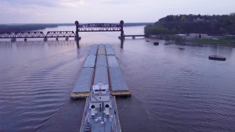 Eine-Wunderschöne-Antenne-Eines-Lastkahns,-Der-Auf-Dem-Mississippi-Zu-Einer-Großen-Stahlzugbrücke-Fährt-Traveling